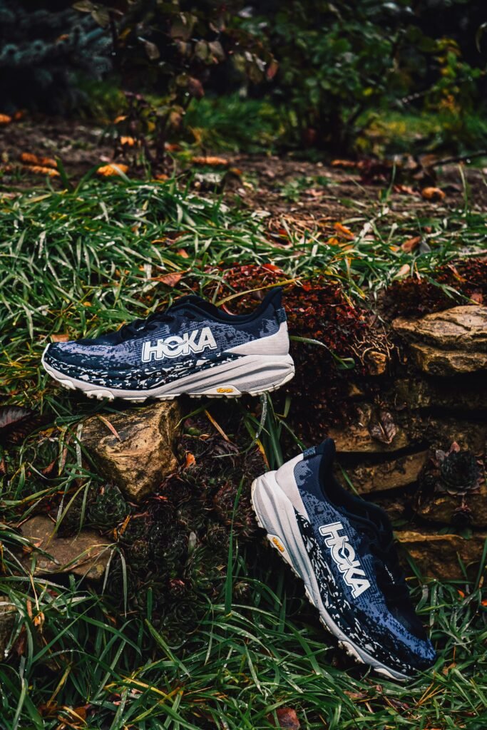 Athletic running shoes on a rocky grassy terrain, perfect for outdoor sports imagery.